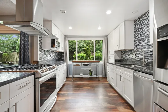 a kitchen with stainless steel appliances granite countertop a stove a sink and a refrigerator
