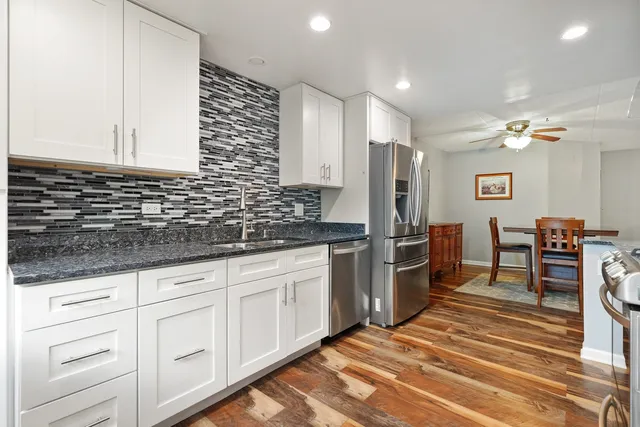 a kitchen with granite countertop a sink cabinets and stainless steel appliances