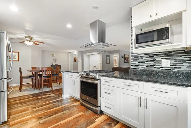 a kitchen with stainless steel appliances granite countertop a stove and white cabinets