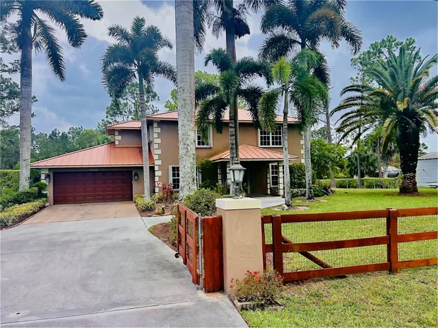 front view of house with a yard and palm trees