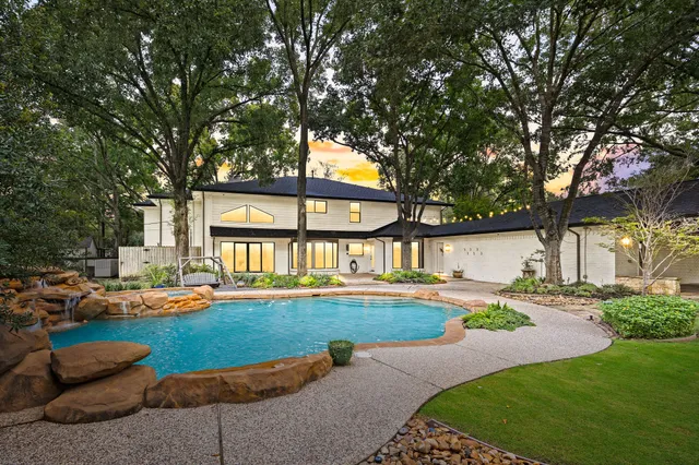 a front view of a house with garden and trees