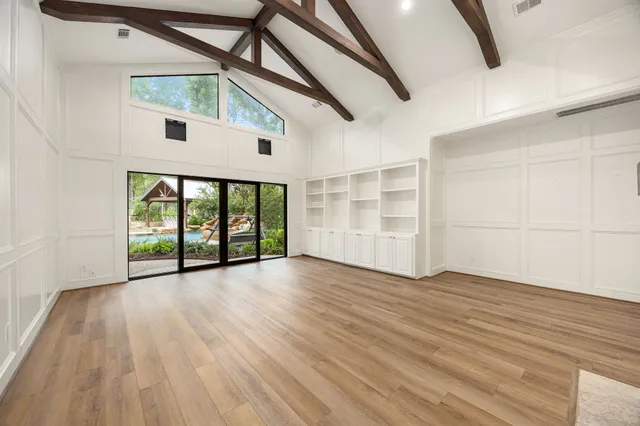 a view of an empty room with wooden floor and windows