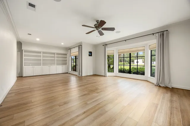 an empty room with wooden floor closet and windows