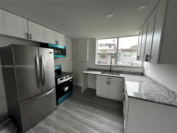 a kitchen with granite countertop stainless steel appliances a refrigerator microwave and sink