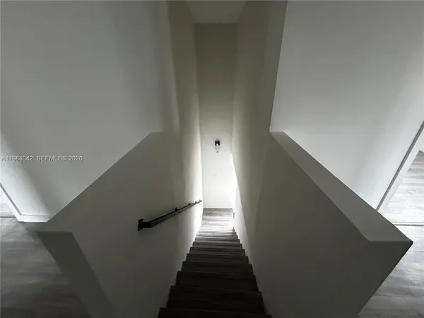 an empty room with wooden floor chandelier fan and windows