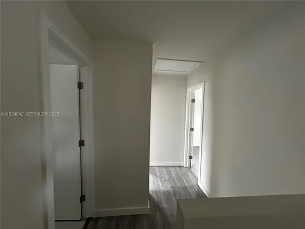 an empty room with wooden floor closet and windows