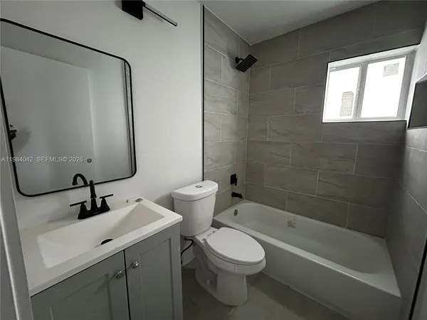 an empty room with wooden floor ceiling fan and windows