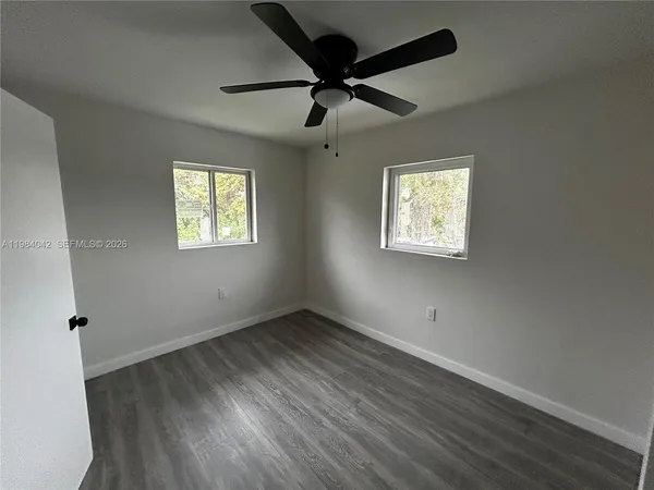 a view of an empty room with a window and wooden floor