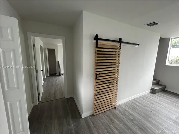a view of an empty room with wooden floor and a window