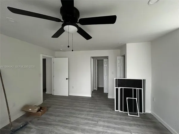 a view of an empty room with a window and wooden floor