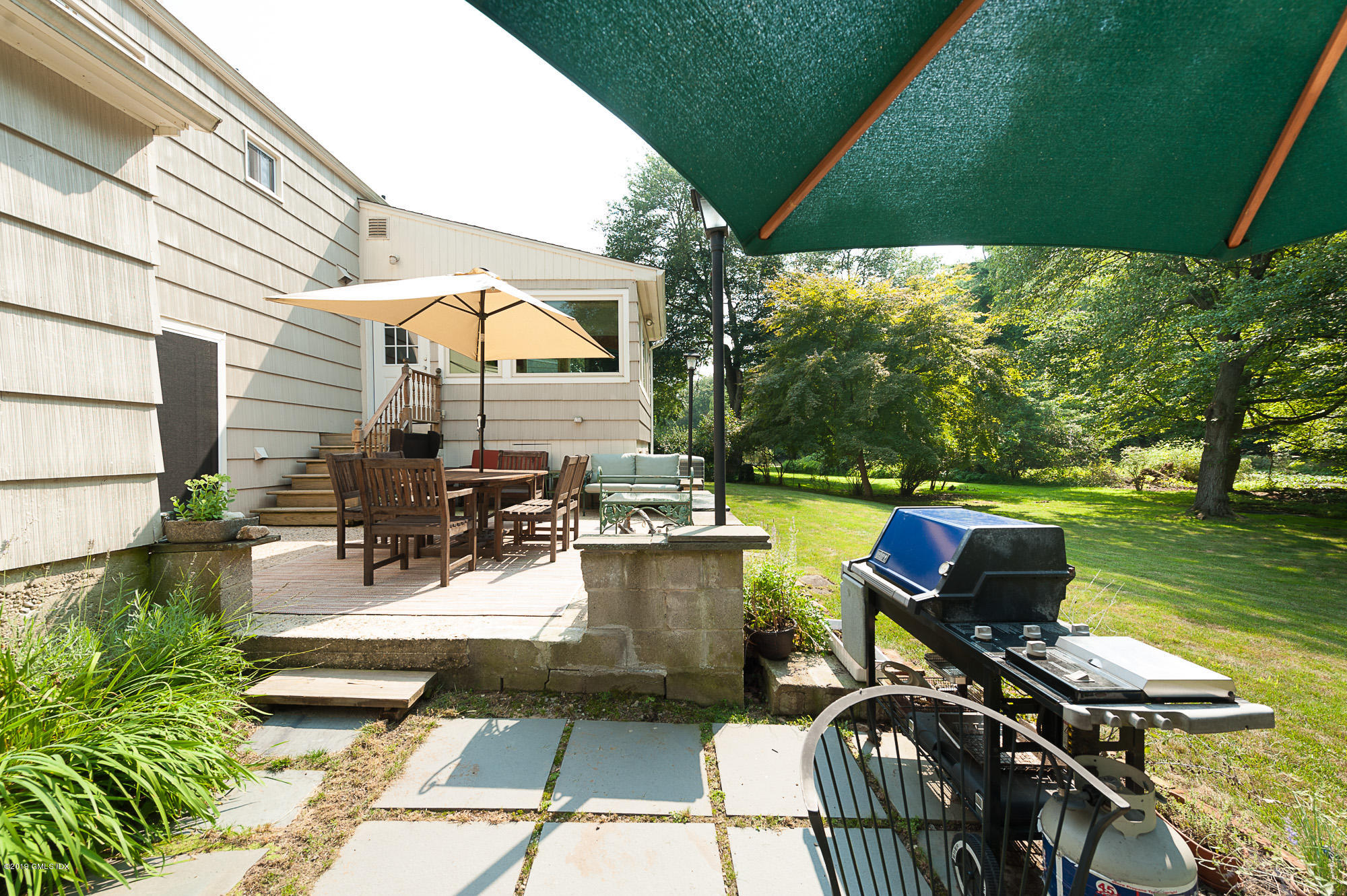 81 Mary Lane Riverside, CT 06878 - Photo 20 of 26 a view of a patio with chairs and table under an umbrella