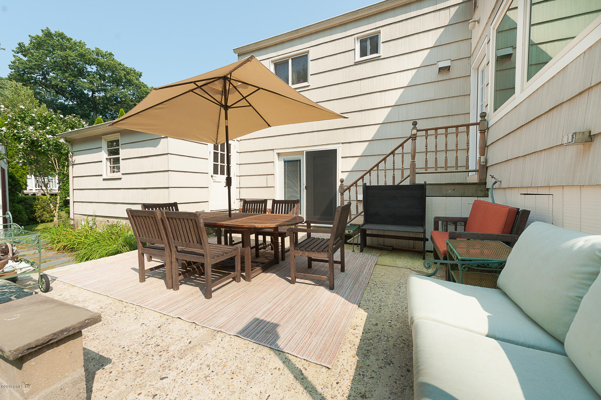 81 Mary Lane Riverside, CT 06878 - Photo 21 of 26 a view of a patio with a table and chairs under an umbrella