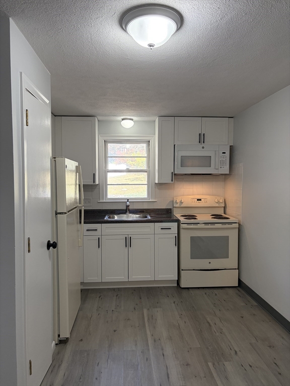 a kitchen with granite countertop a sink cabinets and stainless steel appliances