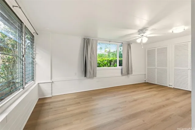 a view of an empty room with a window and wooden floor