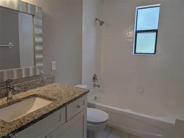 a bathroom with a granite countertop sink a toilet and bathtub
