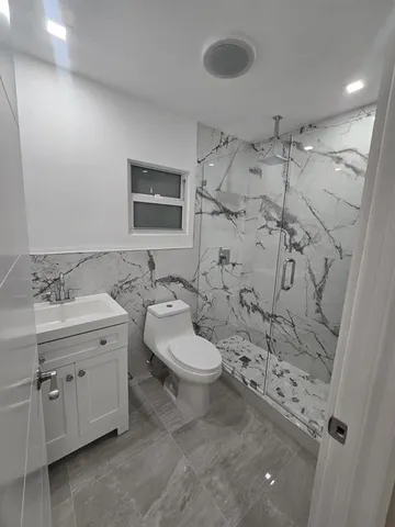 a bathroom with a granite countertop sink a toilet and shower