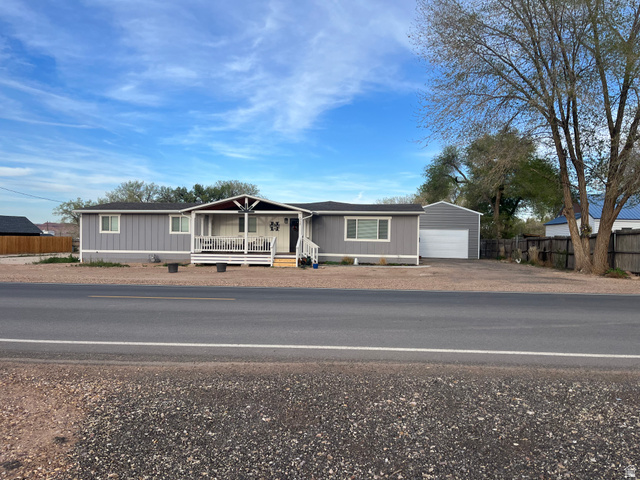 558 North N Cres Road Roosevelt, UT 84066 - Photo 13 of 31 Gray siding residence featuring a covered front porch with white railings, an attached single-car garage, and a gravel driveway