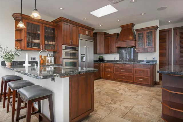 a kitchen with kitchen island granite countertop a stove and a sink