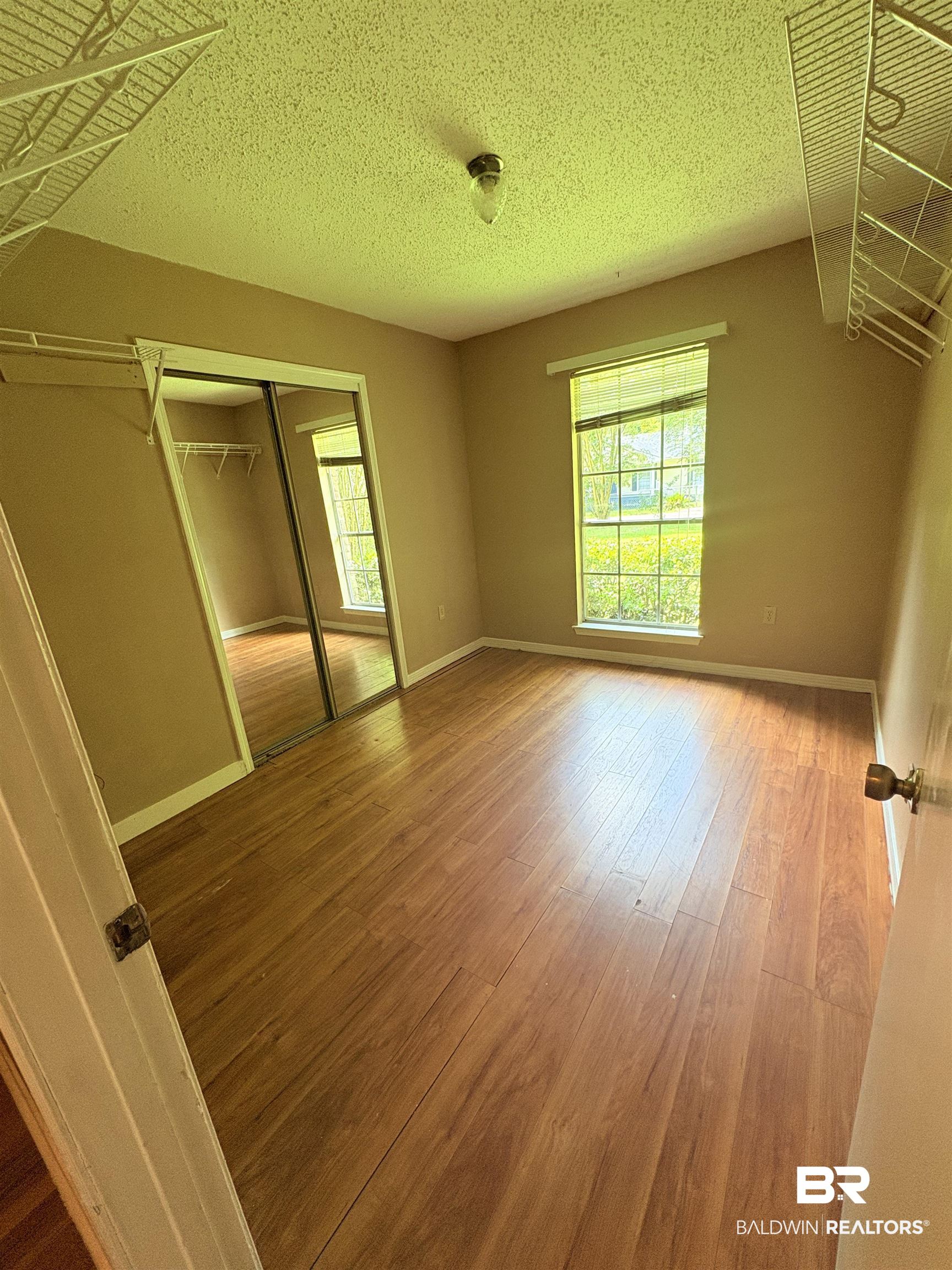 8070 Middle Ring Road Mobile, AL 36619 - Photo 25 of 26 Unfurnished bedroom featuring wood finished floors, a textured ceiling, and a closet