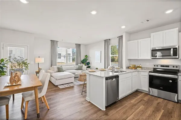 a kitchen with a sink stove cabinets and wooden floor