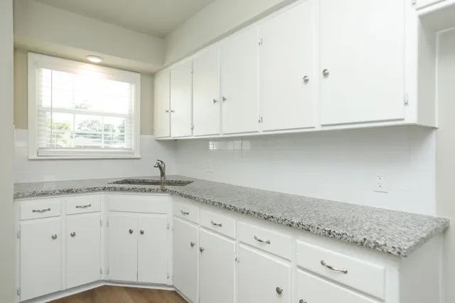 a view of granite countertop white cabinets and a window