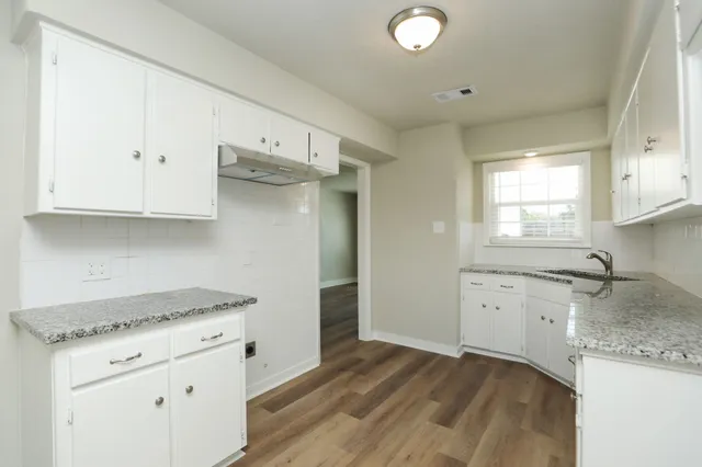 a kitchen with granite countertop a stove a sink and a refrigerator