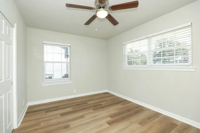 a view of an empty room with wooden floor and a window