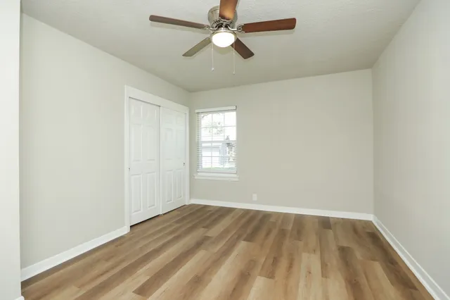 an empty room with a window and a ceiling fan
