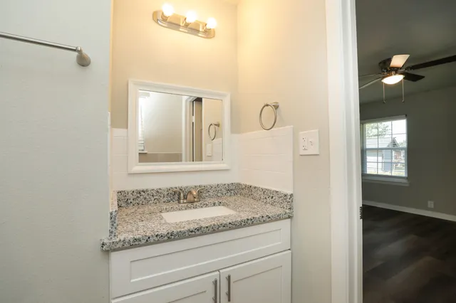 a bathroom with a granite countertop sink and a mirror