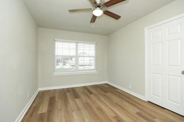 a view of empty room with wooden floor and fan