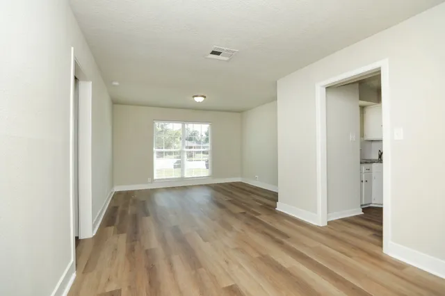 an empty room with wooden floor and windows