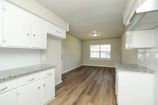a kitchen with granite countertop white cabinets and a wooden floor