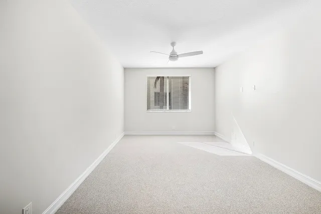 an empty room with a window and a kitchen