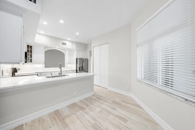 a large white kitchen with a sink a window and a counter top space