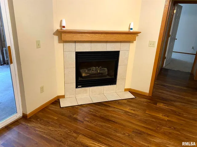 a view of an empty room with wooden floor and a fireplace