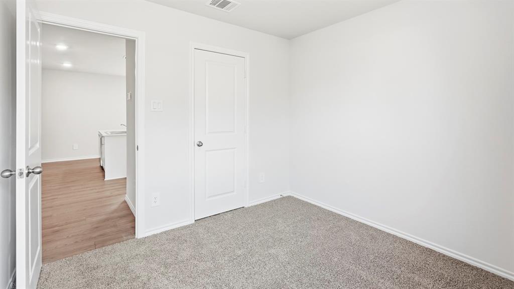3319 Twilight Trail Forney, TX 75126 - Photo 27 of 33 Carpeted room featuring light gray walls, white trim, and a white interior door with brushed nickel hardware
