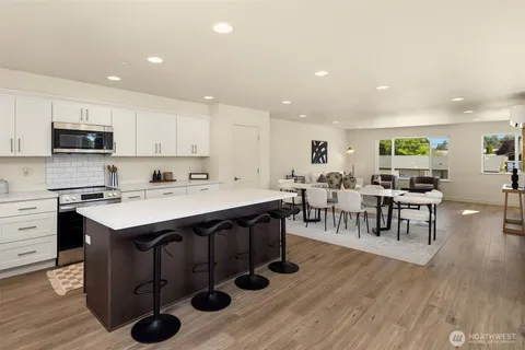 a kitchen with stainless steel appliances granite countertop a stove a sink dishwasher and a refrigerator with wooden floor