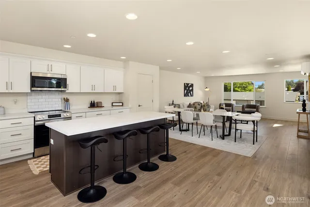 a kitchen with stainless steel appliances granite countertop a stove a sink dishwasher and a refrigerator with wooden floor