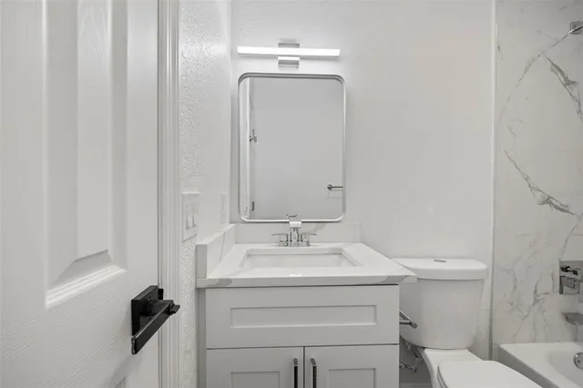 a bathroom with a sink vanity mirror and toilet