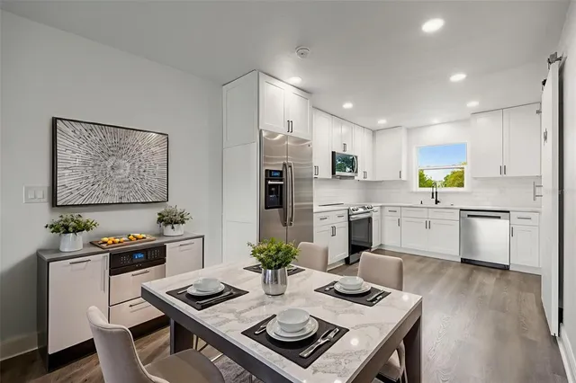 a living room with stainless steel appliances furniture a dining table and chairs