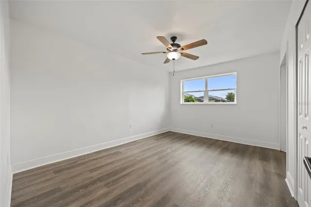 an empty room with wooden floor fan and windows