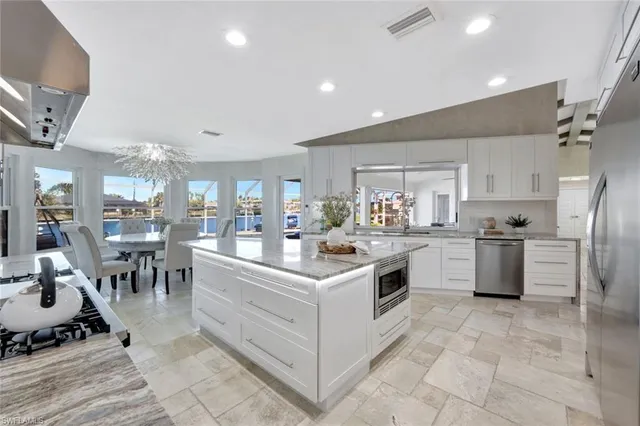 a large white kitchen with lots of counter top space and stainless steel appliances
