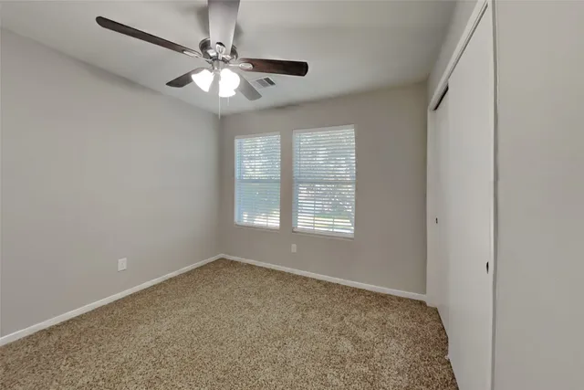 an empty room with windows and chandelier fan