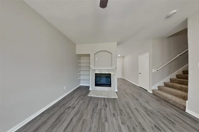 an empty room with wooden floor fireplace and windows