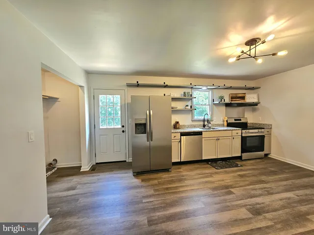 a kitchen with stainless steel appliances kitchen island granite countertop a refrigerator and a stove top oven