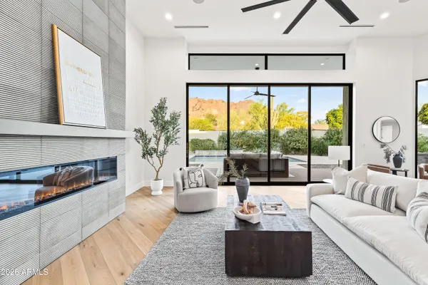 a living room with furniture large window and wooden floor