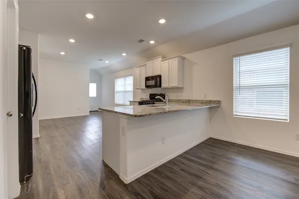 a kitchen with stainless steel appliances granite countertop a refrigerator a stove top oven a sink and dishwasher with wooden floor