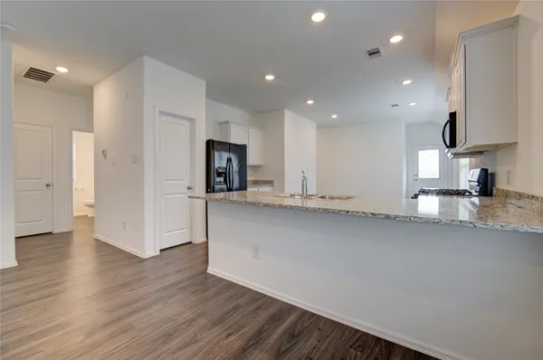 a view of a kitchen with center island wooden floor and a sink