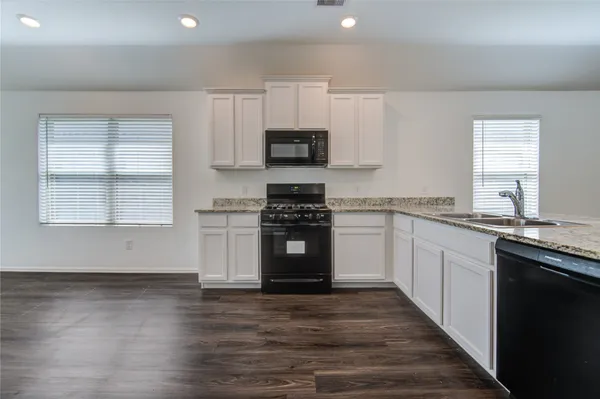 a kitchen with granite countertop a stove top oven sink and cabinets
