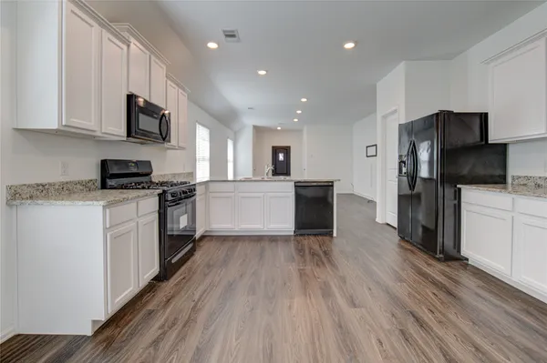 a large kitchen with cabinets wooden floor and stainless steel appliances
